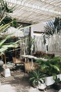 Woven chairs on a balcony next to tropical plants - might just have the makings of a good apartment..