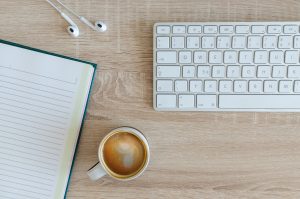 Coffee, keyboard, ear pods and notebook.