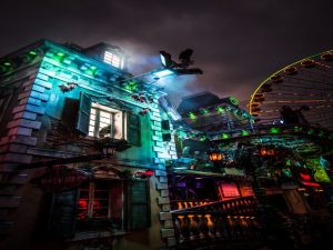 A haunted house next to a Ferris wheel during nighttime.