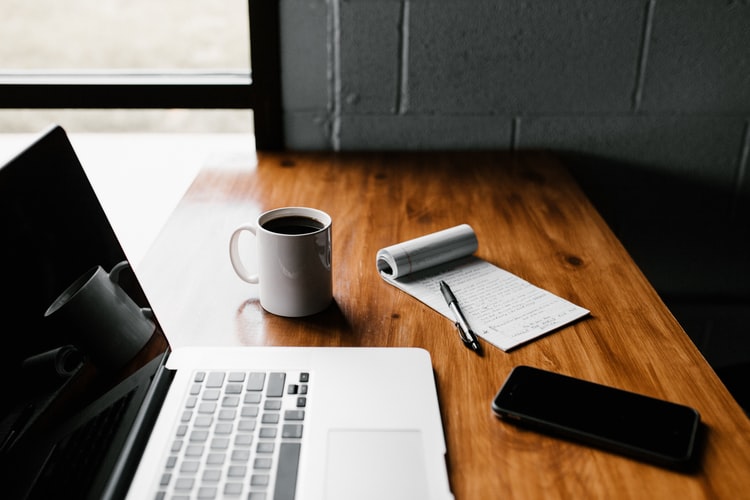 laptop, coffee mug and a phone on the desk