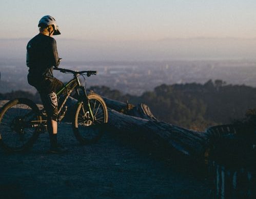 man riding on bicycle while standing on peak