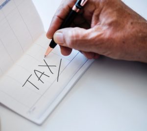 Hand writing TAX on a sheet of paper