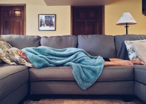 Person napping on a couch under a blanket after moving from Idaho to California 