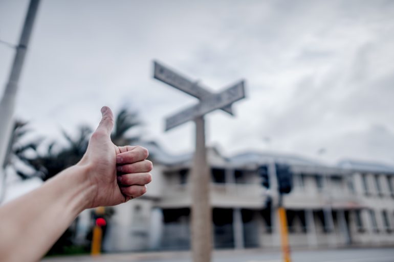 Person showing thumbs up at a crossroad.