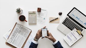 hands holding phone, laptop and papers 