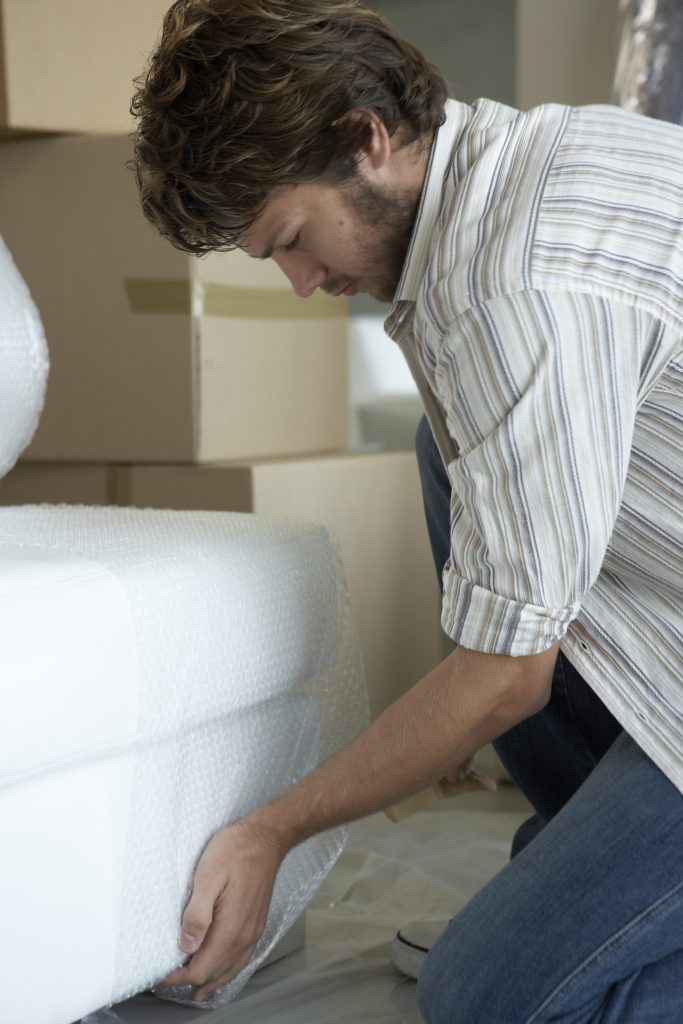 Man wrapping furniture in bubble wrap