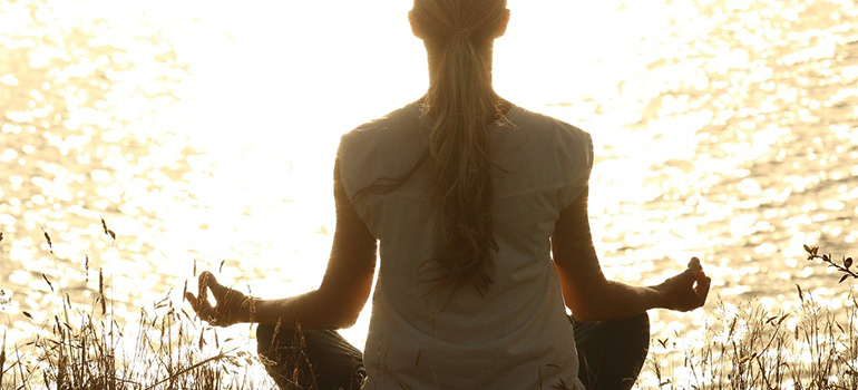 A woman meditating near a water surface