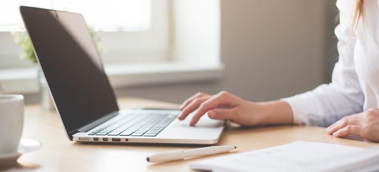 A woman typing on a laptop - you need to research cross country moving companies Minneapolis before making a decision