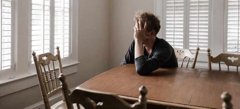 A man sitting at a table, holding his head