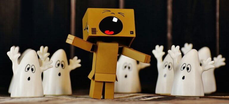 A toy person made of tiny boxes scared of toy ghosts