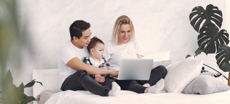Man, woman and their child sitting in front of laptop and reading about cross country moving companies Portland
