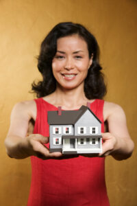 woman holding a small house representing the need to find a home before moving from Colorado to Tennessee
