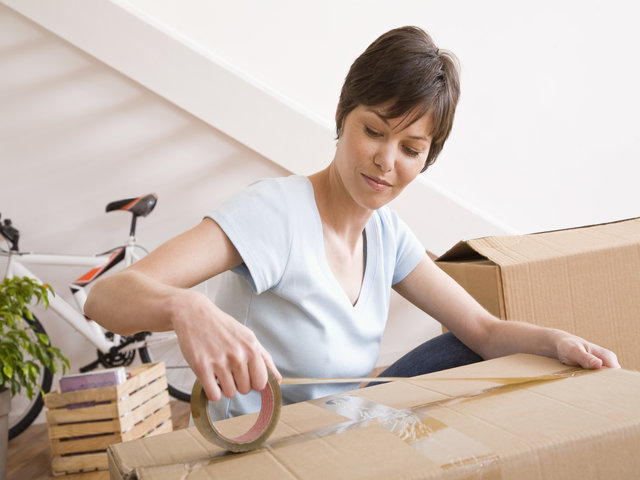 Women taping a cardboard moving box