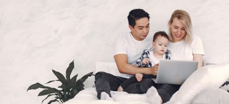 Man and a woman holding their child and reading about how to find cross country moving companies Columbia on their laptop