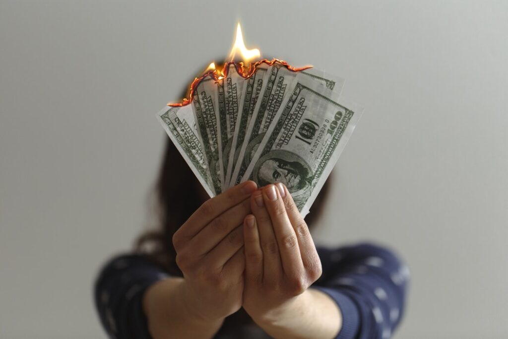 Person holding burning bills.