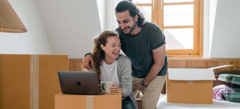 Couple smiling while looking for cross country moving companies Barre on their laptop