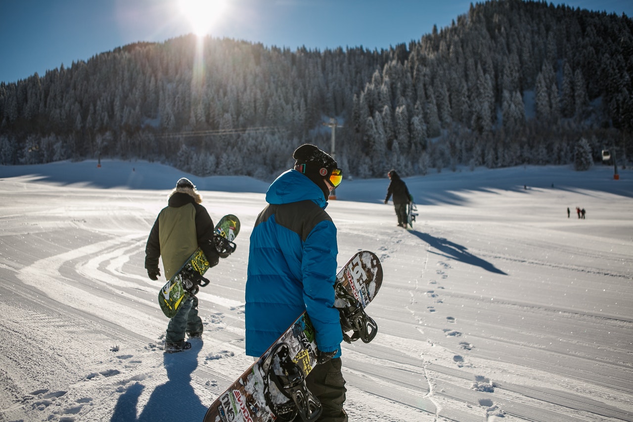 people holding snowboards on a snowy field