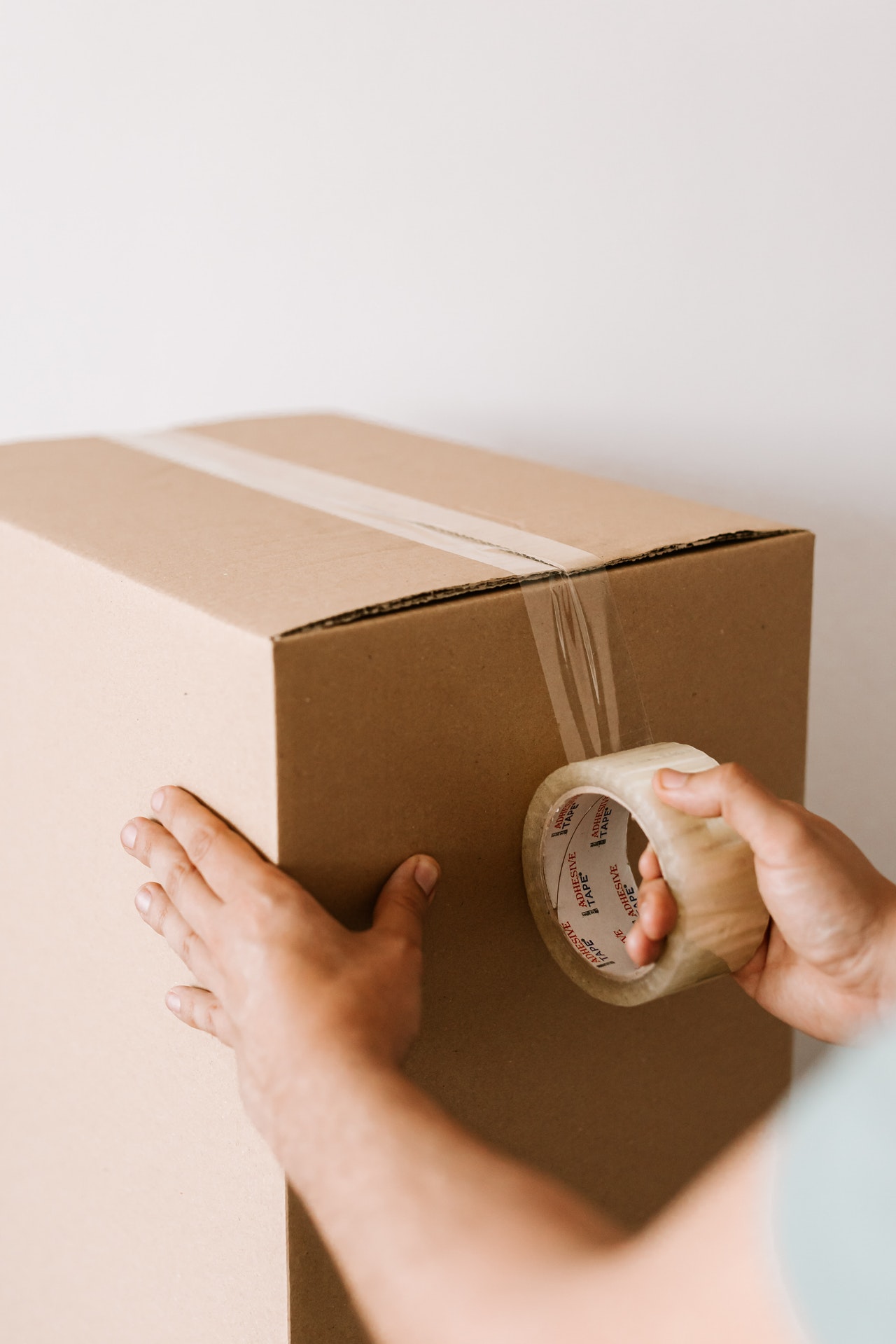 man sealing a moving box