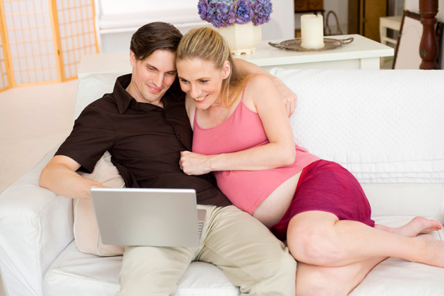 A man and a pregnant woman looking at a computer