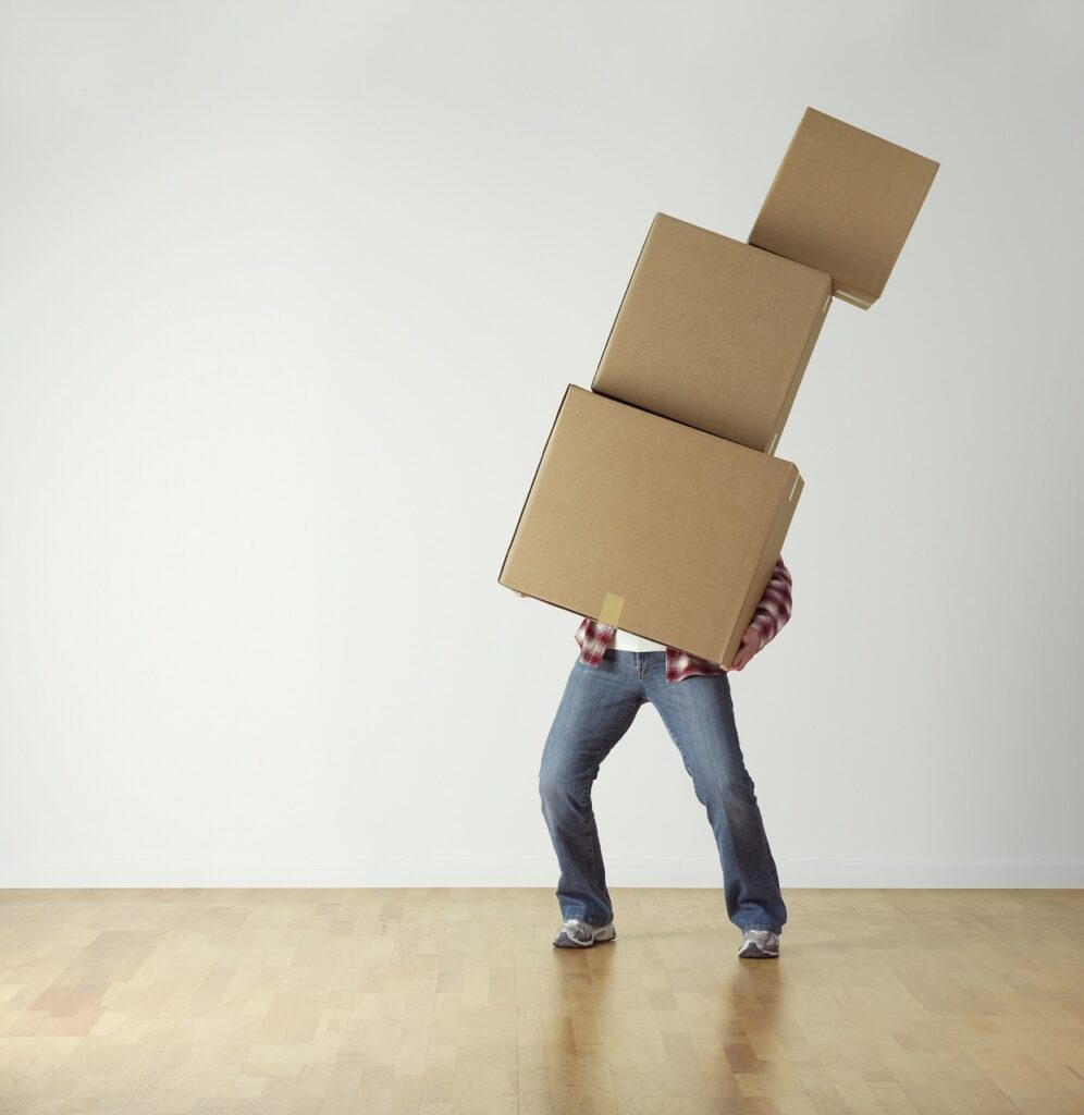 a man holding a stack of cardboard boxes with the top box falling off