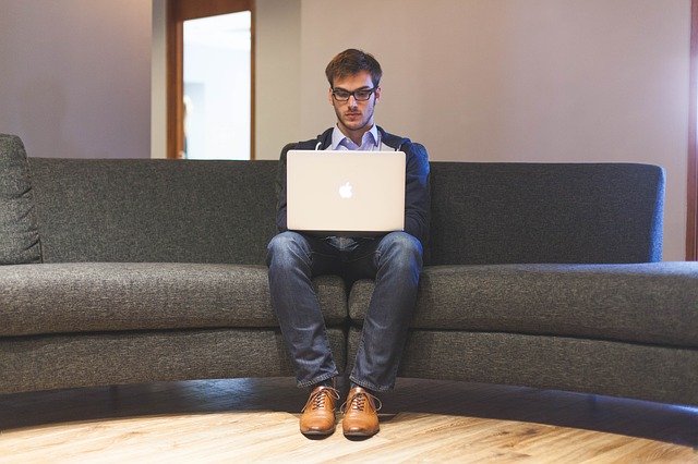 a man sitting on a couch and using computer