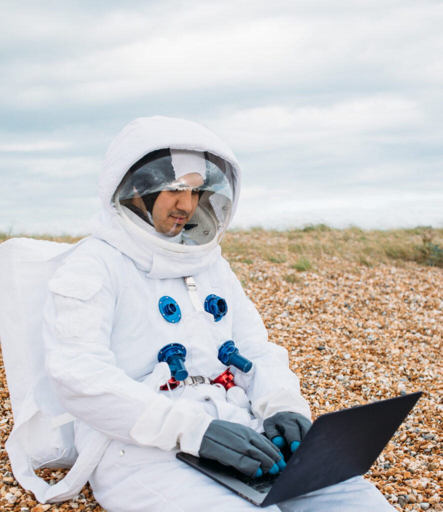 A person in a space suit typing on a laptop