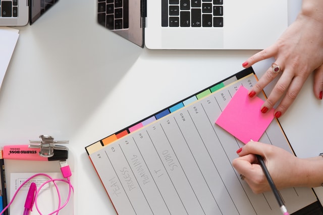 person writing on a post-it note