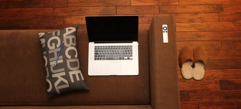 A laptop on the couch, next to a pillow.