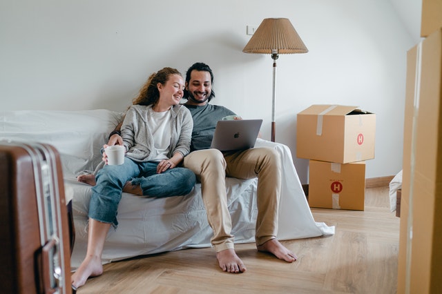 Man and a woman sitting on a sofa surrounded by moving boxes