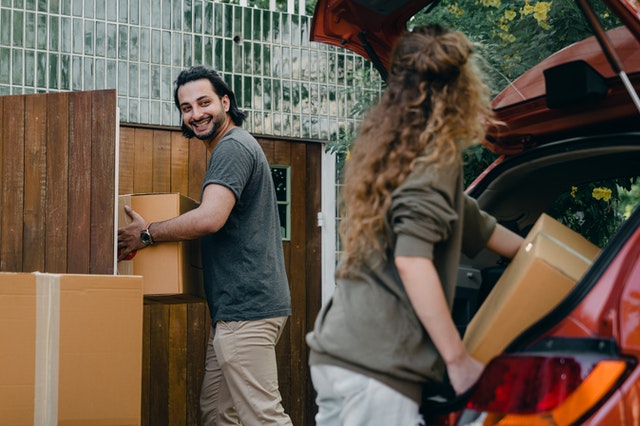 A couple packing boxes in the trunk of a car