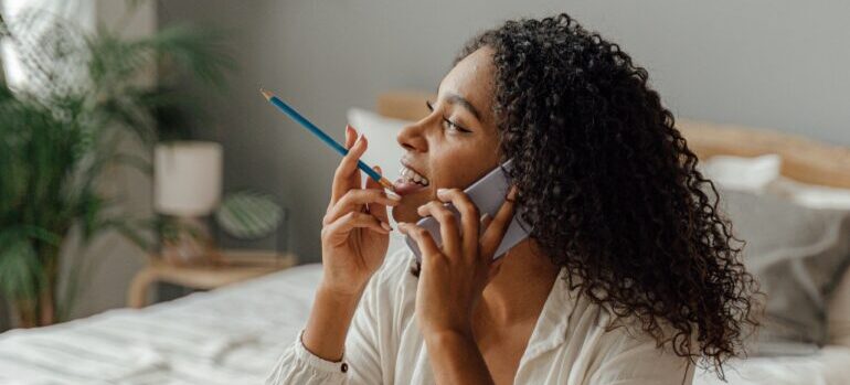 A woman holding a pencil while making a phone call.
