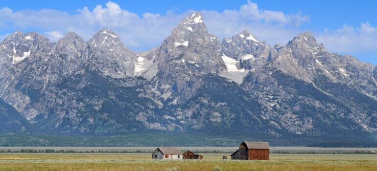 A couple of houses on a plain in Wyoming beneath mountains.