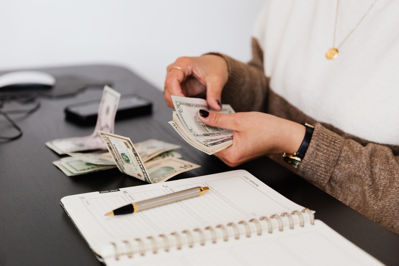 a woman counting money after calculating something at the table