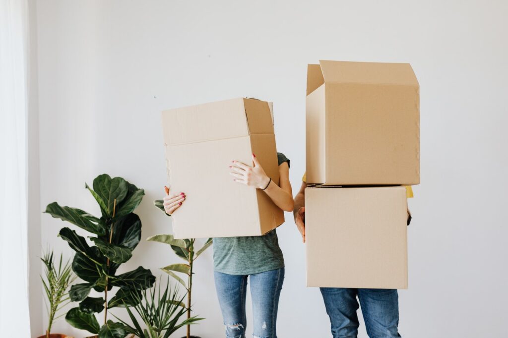 Couple carrying cardboard boxes in living room