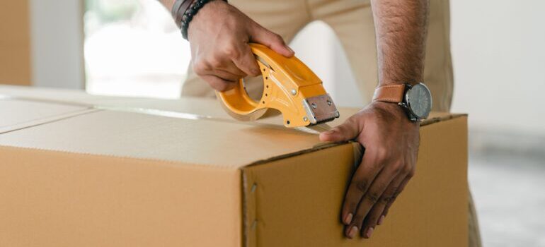 A man taping a moving box