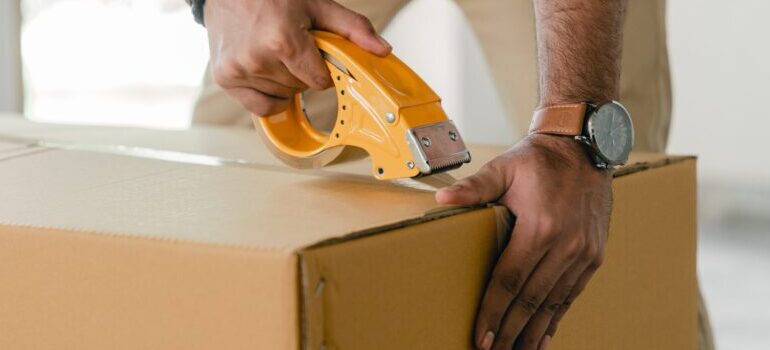person sealing up a cardboard box