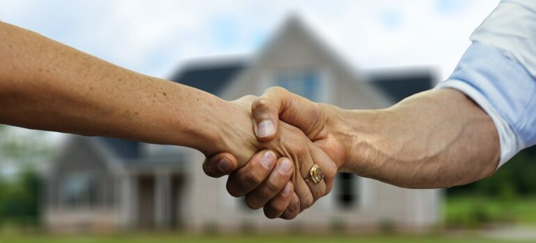 A handshake in front of a house. 