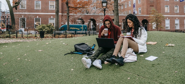 Boy and girl sitting on grass in college yard