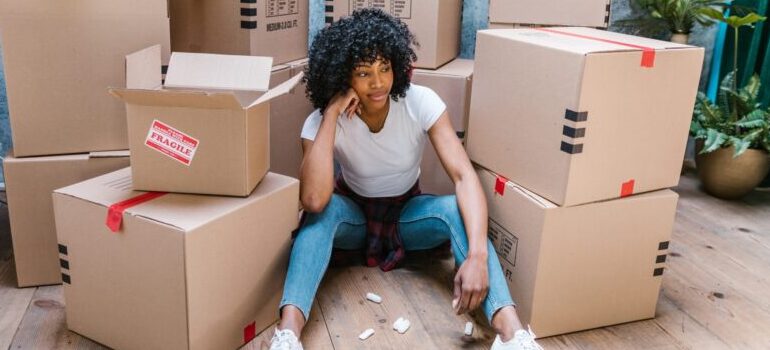woman sitting among cardboard moving boxes