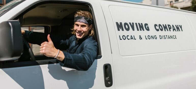person sitting in a moving van, smiling, thumb up