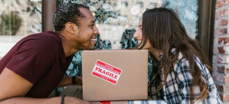 Man and woman holding a box with a label fragile