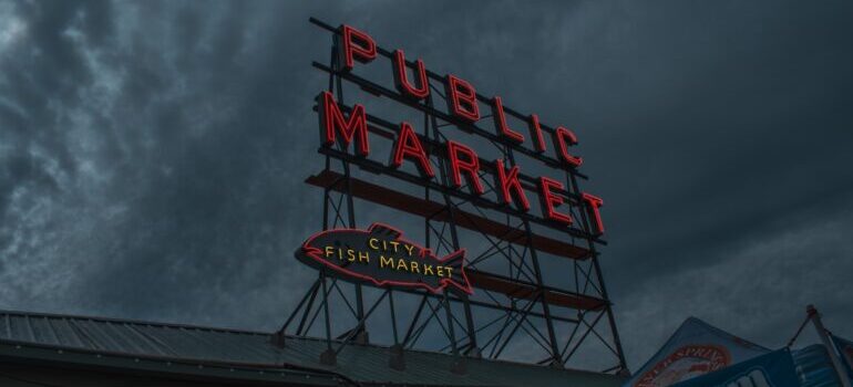 red public market sign in seattle with the clouds in the background