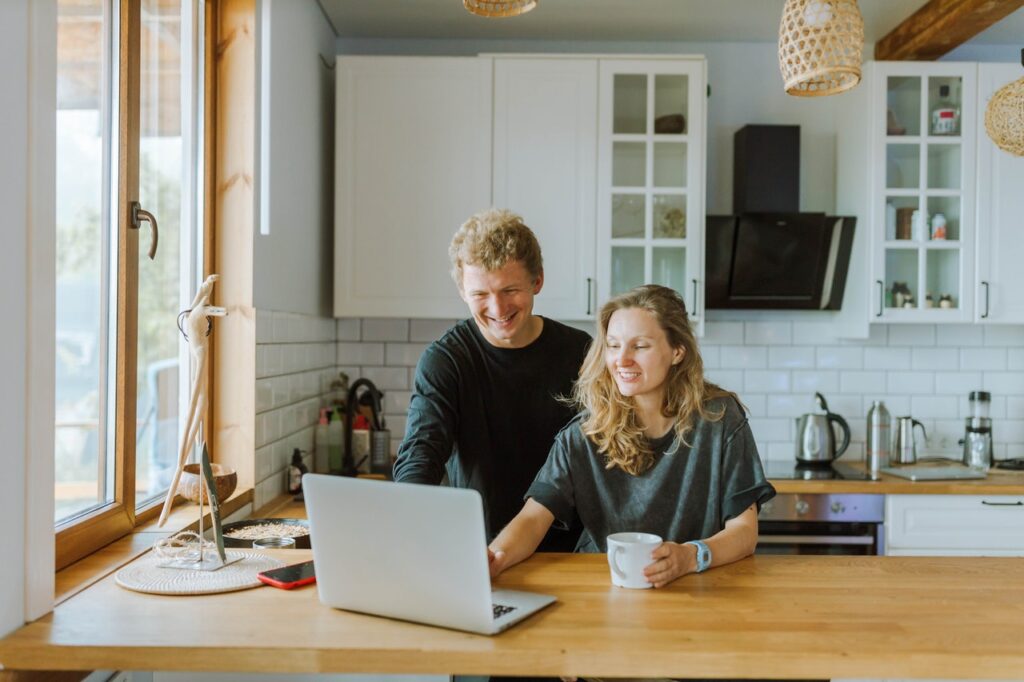 Two people conducting internet research on a laptop, smiling