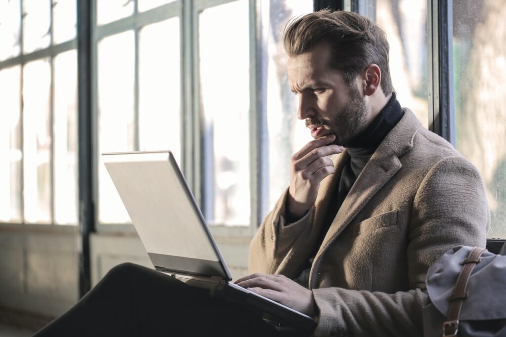 A man reading something on his laptop, looking rather intrigued