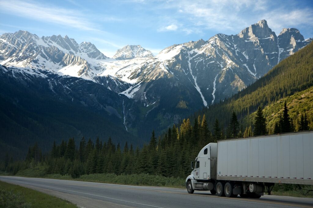 A truck on a highway with mountains in the background