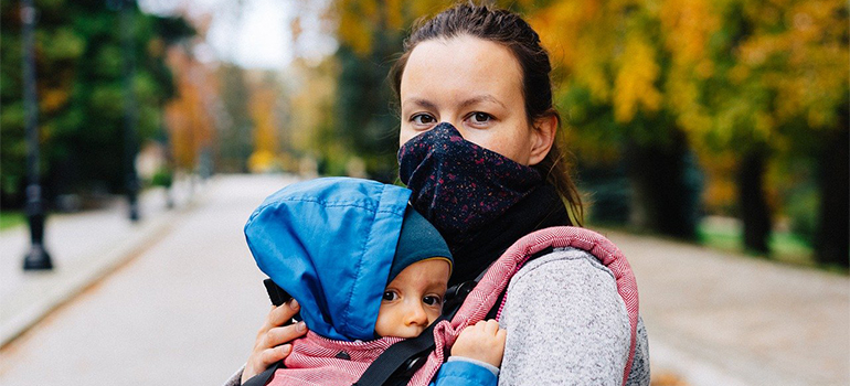 a mom holding a child while wearing a mask