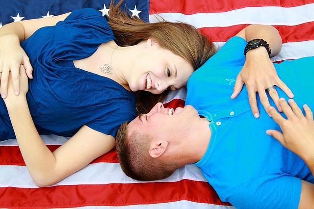 a man and a woman laying on a US flag
