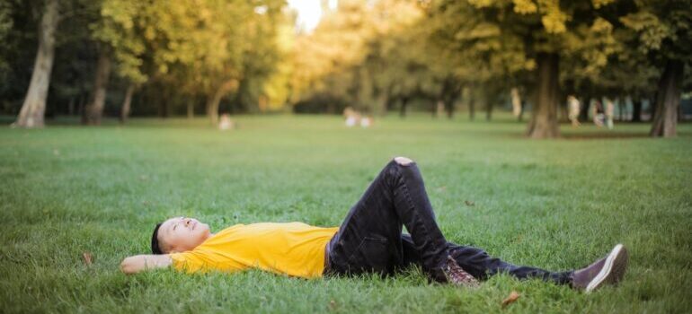 A man laying on the grass and thinking about whether he's ready to move to New York City.