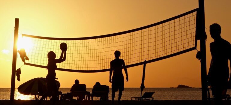 A group of friends playing volleyball on the beach after moving from NYC to Miami