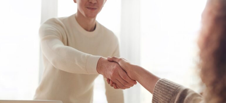 A moving company employee shaking hands with a client whos on a budget after finding a way to appeal to customers with a low budget.